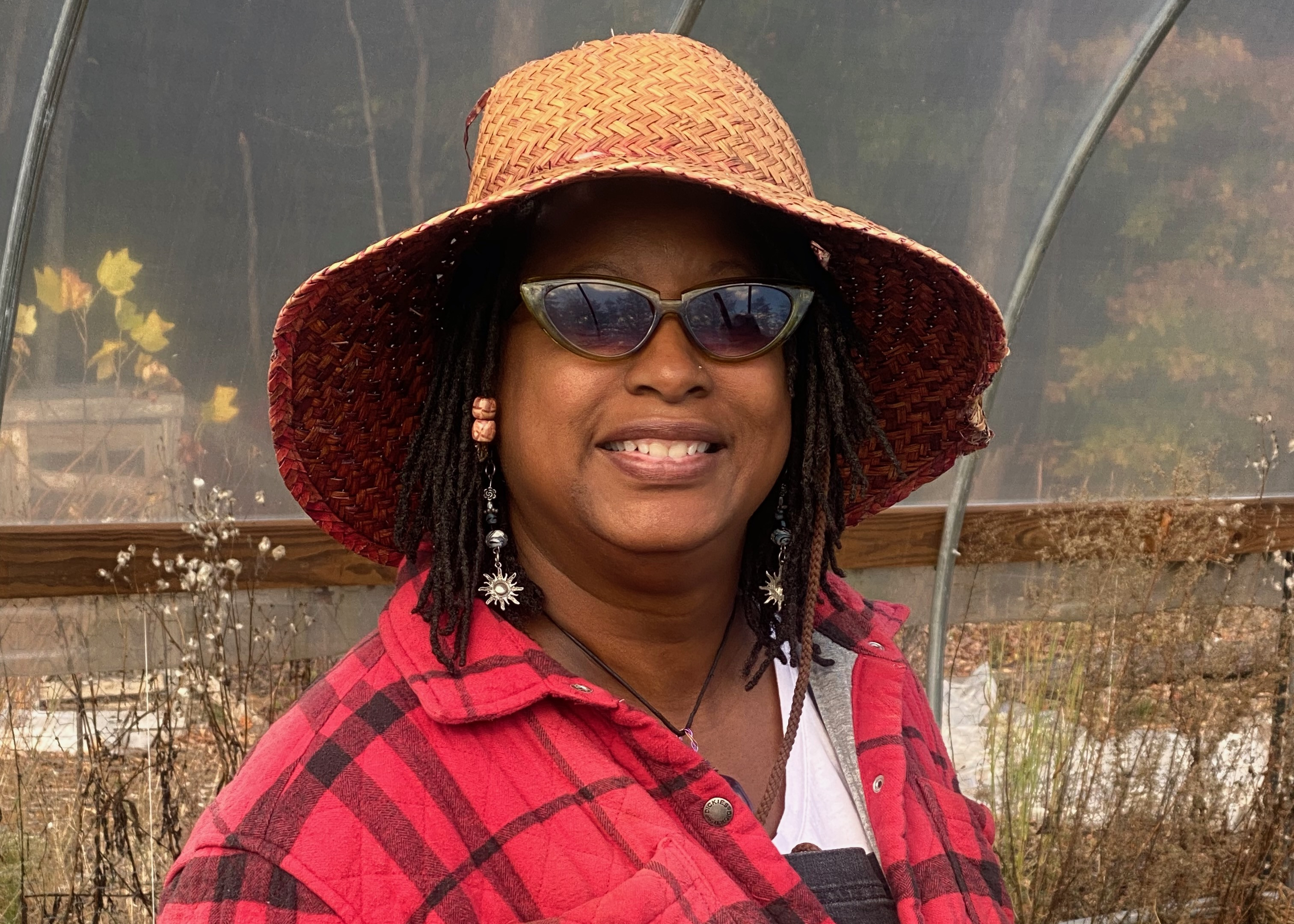 Smiling woman farmer in hat and sunglasses.