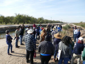 Latino farmers stand by irrigation canal in San Joaquin Valley.