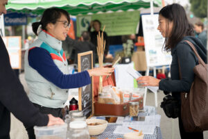 Two people at a farmers market discuss heirloom grains.