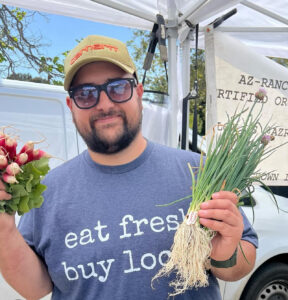 California farmer with radishes and leeks at farmers market