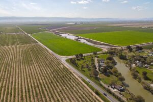 Drone shot of San Joaquin Valley with orchards, houses and river.