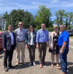 A group of men and women with Chelsea Gazillo in a farm field.